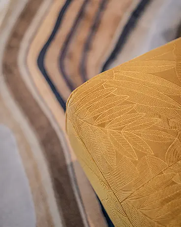 Detail eines Sofals mit gelbem Bezug mit floralem ton-in-ton Muster