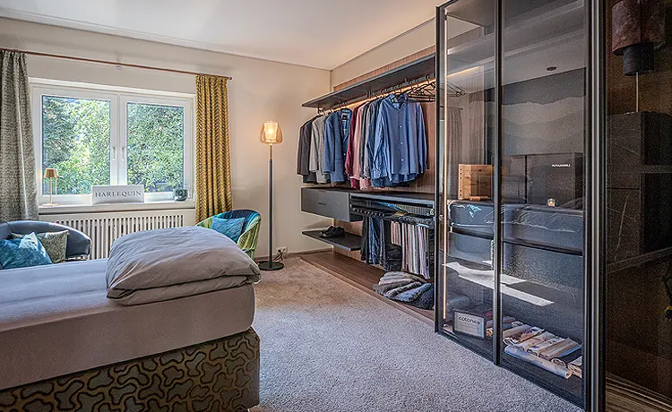 Blick in ein Schlafzimmer mit Bett, auf der gegenüberliegenden Seite befindet sich ein großer Schrank. 