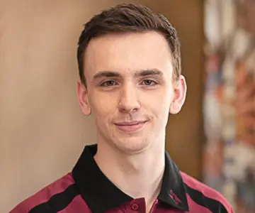 Ein junger Mann etwa Mitte zwanzig mit kurzen braunen Haaren.